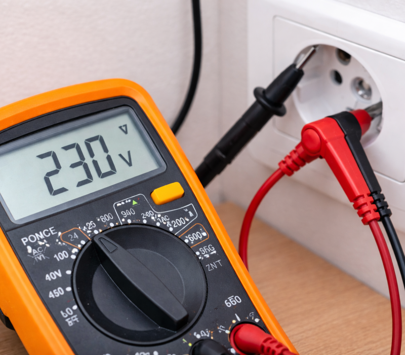 PAT testi sırasında prizde gerilim ölçümü yapan dijital multimetre ile taşınabilir elektrikli cihaz güvenlik kontrolü